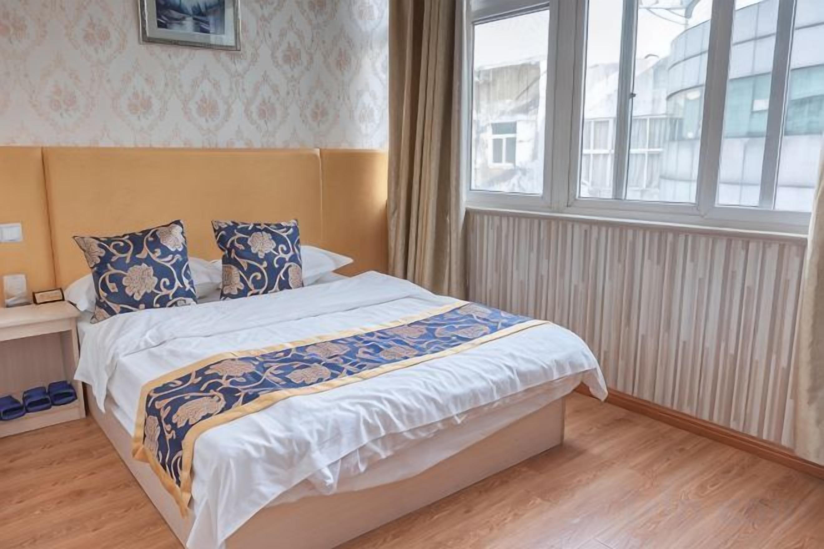 Een hotelkamer met een groot bed, een nachtkastje, een raam met uitzicht en een kamer met een patroon op de muur.
