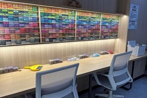 A reception desk with a wall of colorful gift boxes, two chairs, and a sign on the wall. - LinghangHostel (Shenzhen)