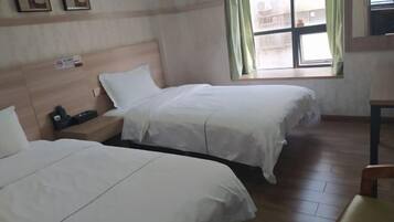 Une chambre d’hôtel avec deux lits, une table de chevet, une fenêtre avec des rideaux et une vue sur l’extérieur.