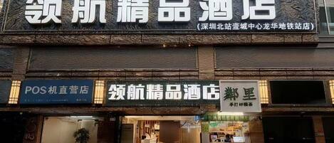A hotel facade with signage for a POS kiosk and a hotel named '领航精品酒店'.