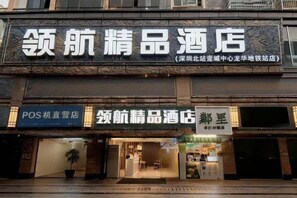 Fachada de hotel con señalización para un quiosco de punto de venta y un hotel llamado 领航精品酒店.