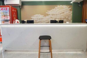 A reception desk with a traditional architectural mural, a bar area, and a stool. - LinghangHostel (Shenzhen)