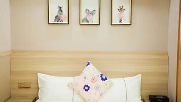 A hotel room with a wooden headboard, a bed with white bedding, a floral pillow, and three framed animal pictures on the wall.