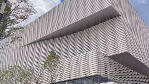 A modern building with a unique wavy facade, large windows, and a clear sky. - LinghangHostel (Shenzhen)