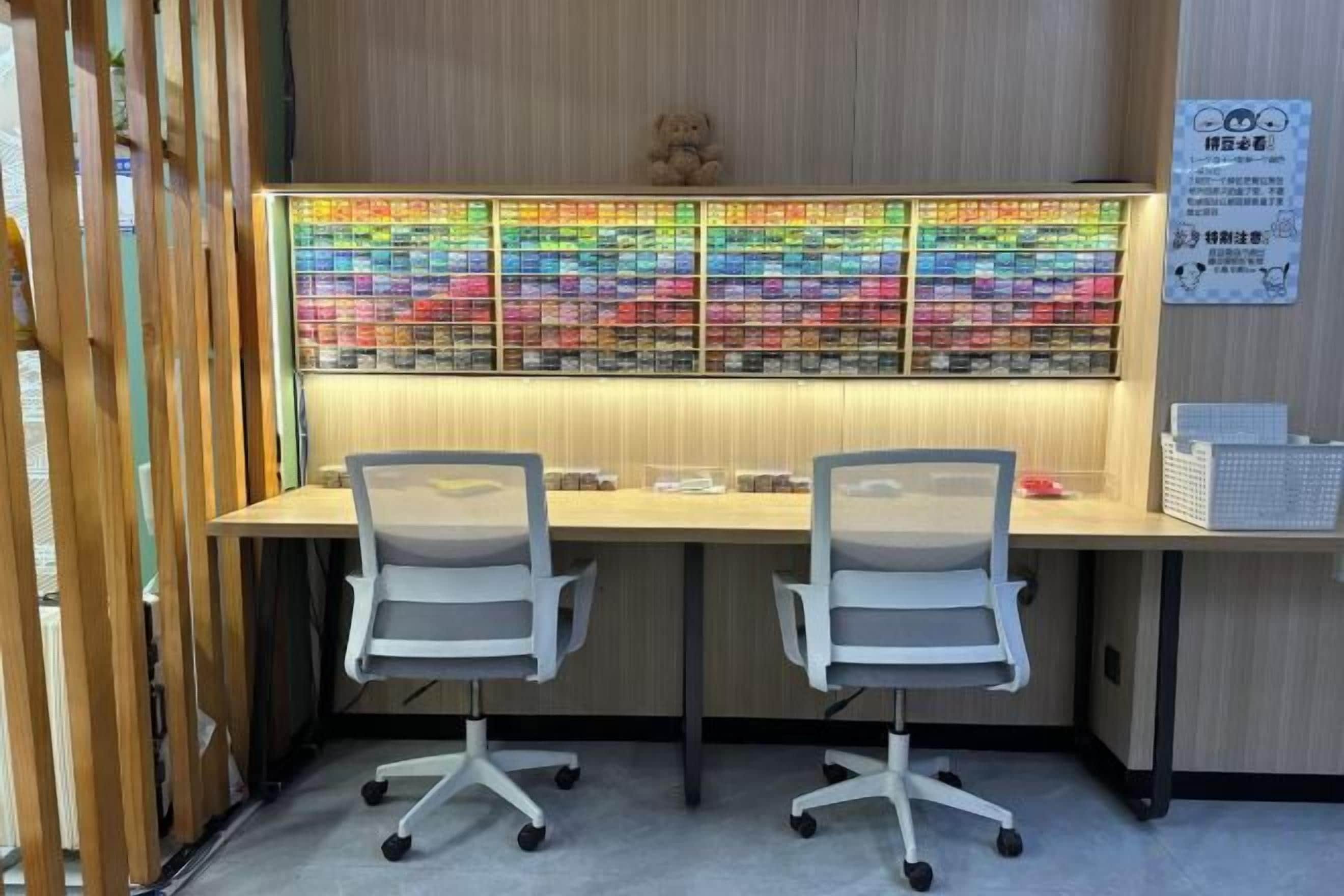 Een werkplek met twee bureaustoelen, een bureau en een groot wandgemonteerd scherm.