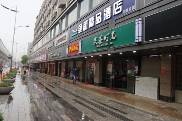 A street with various storefronts, including a hotel and a fruit and vegetable shop. - LinghangHostel (Shenzhen)