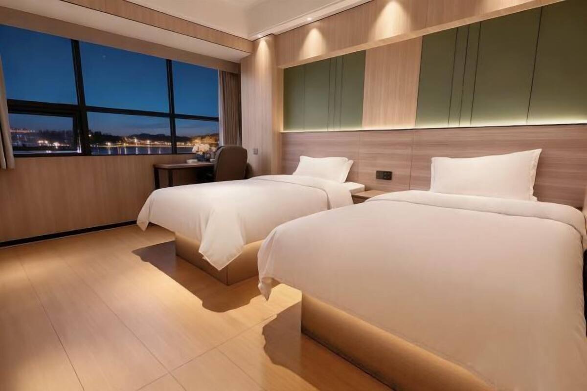 A hotel room with two beds, a desk, and a view of a body of water.