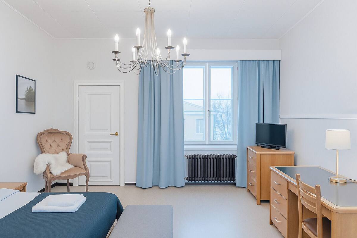 Ein Hotelzimmer mit einem Bett, einem Sessel, einem Schreibtisch, einem Fernseher und einer Heizung.