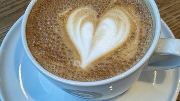Eine Tasse Kaffee mit herzförmiger Latte-Kunst auf einem Untertasse.