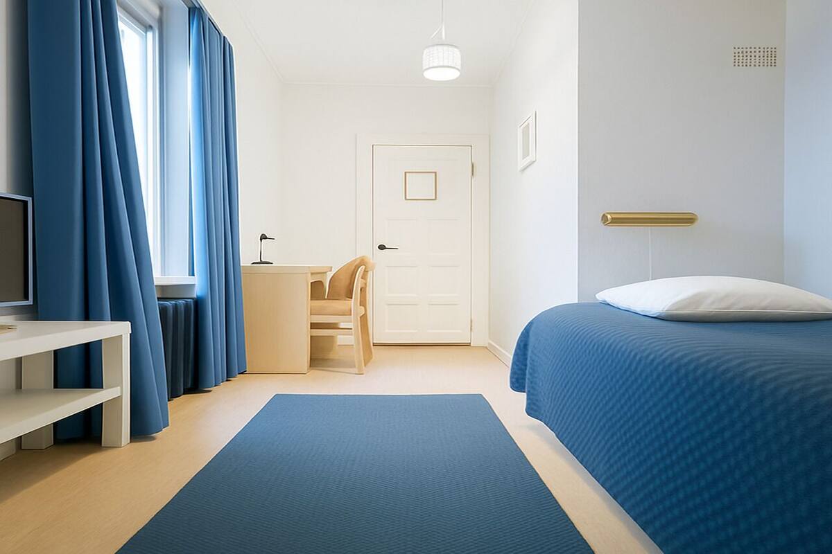 Ein modernes Schlafzimmer mit Bett, Schreibtisch, Stuhl und einem Fenster mit Vorhängen.
