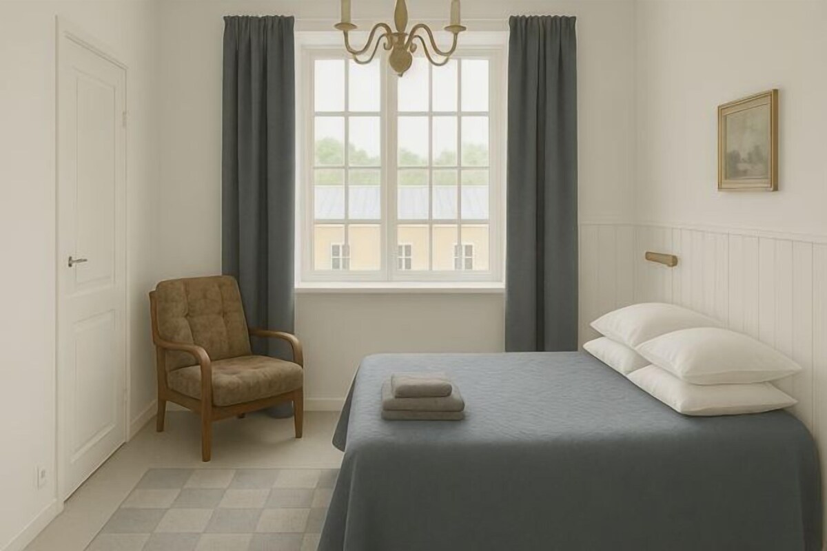 Un dormitorio con cama, silla, ventana y candelabro.