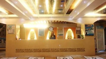 A reception desk with a clock, framed artwork, and a patterned carpet.