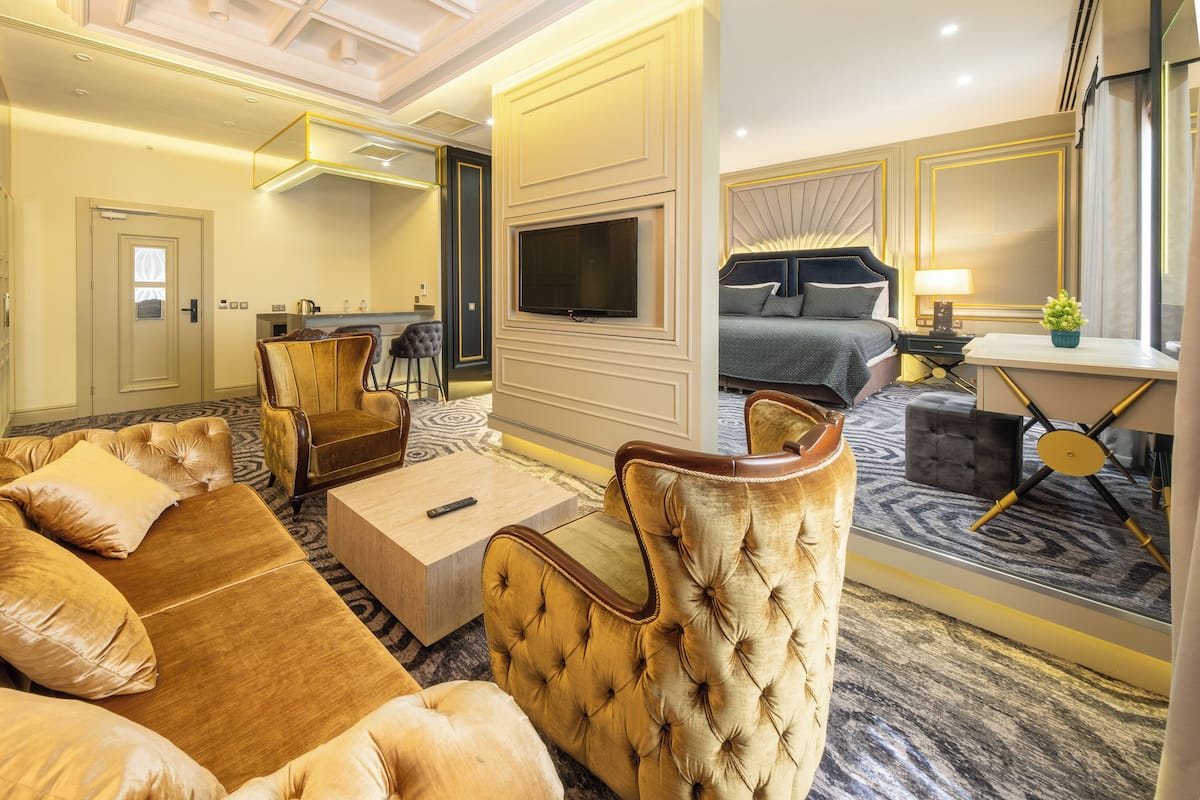 Una habitación de hotel con un sofá grande, televisión, zona de comedor y dormitorio.
