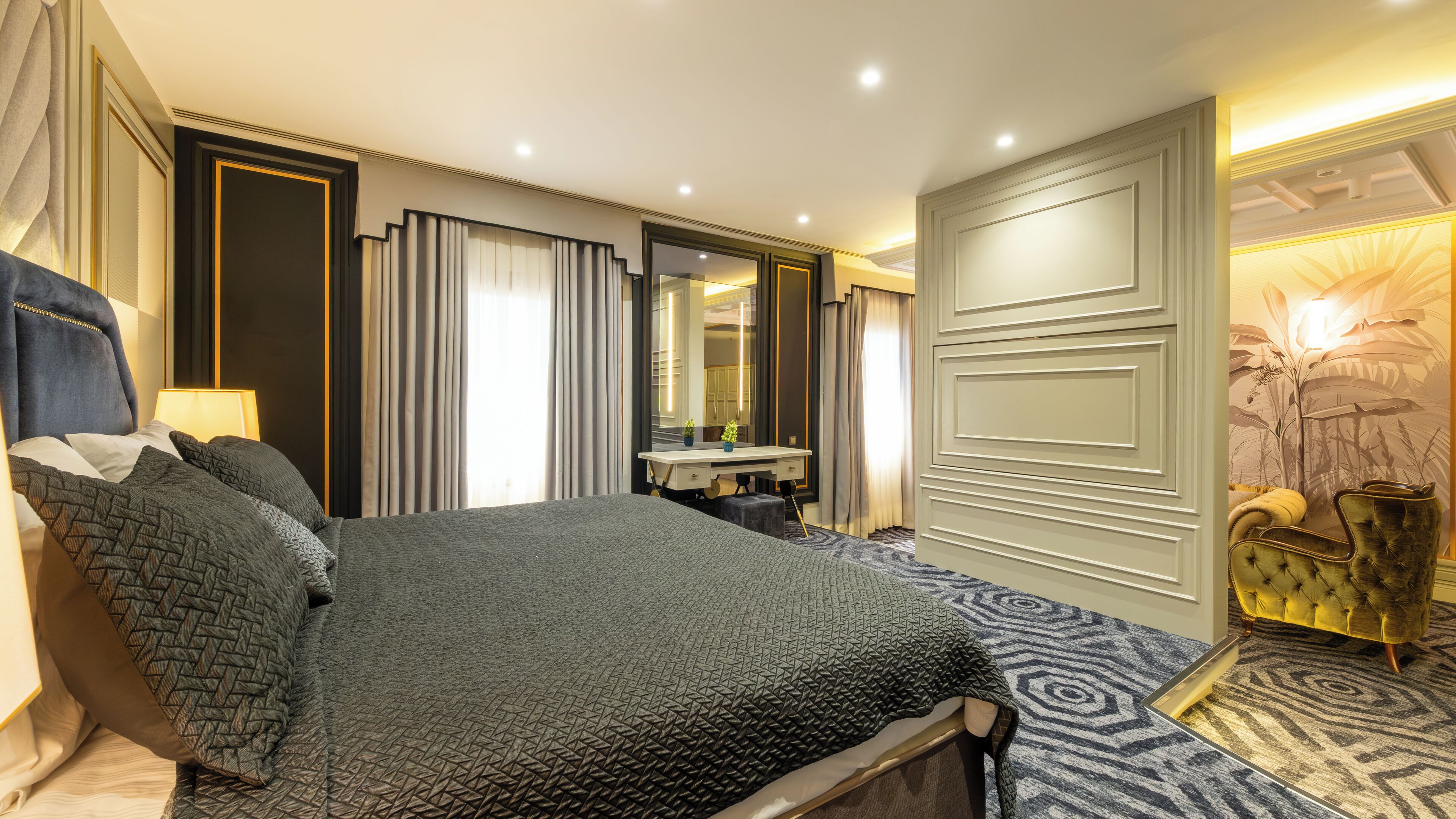 Una habitación de hotel moderna con una cama grande, un tocador con espejo y un panel decorativo en la pared.