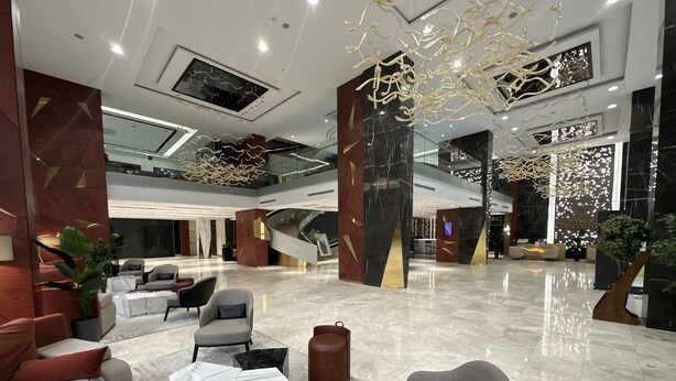 A spacious lobby with a modern design, featuring a marble floor, contemporary furniture, and a central staircase. - Teymur Continental Hotel (Gaziantep)