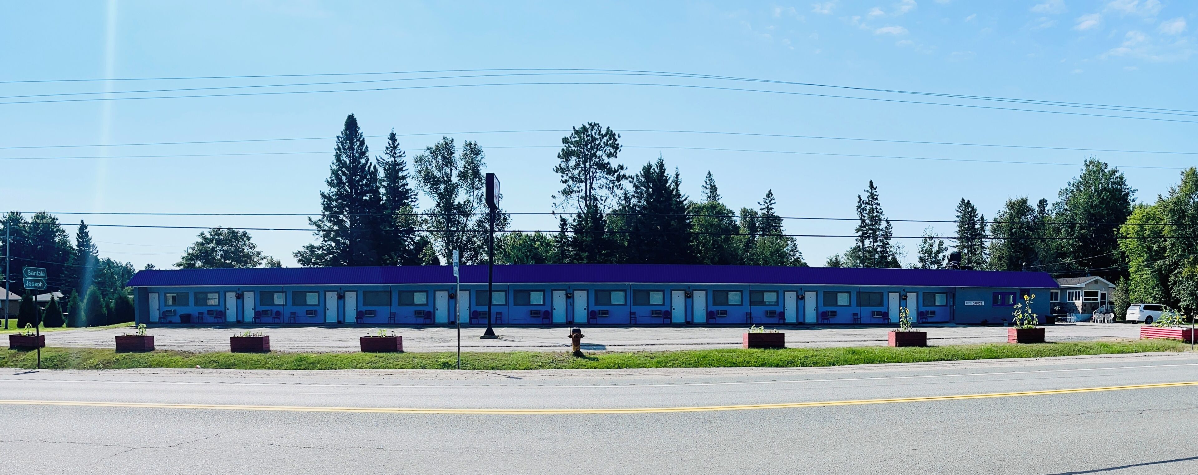 Un motel amb una filera d'habitacions, un pàrquing i un petit edifici d'oficines.