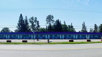 Un motel amb una filera d'habitacions, un pàrquing i un petit edifici d'oficines.