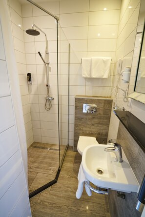 A modern bathroom with a glass-enclosed shower, a white sink, and a mirror above the sink. - Hotel The Bird (Amsterdam)