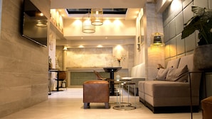 A modern interior with a sofa, ottoman, and a dining table with chairs. - Hotel The Bird (Amsterdam)