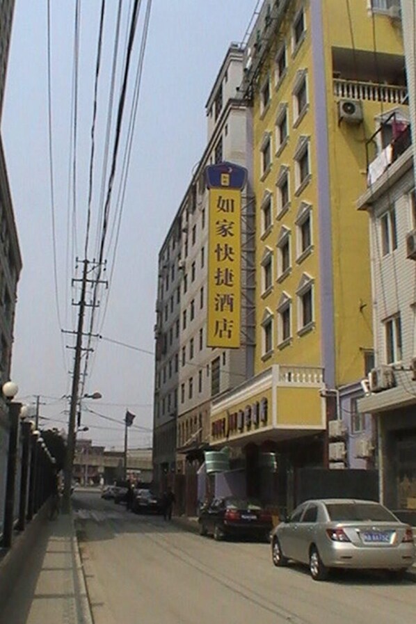 A street view with a yellow building featuring a vertical sign with Chinese characters.