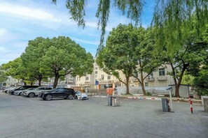 Ein Parkplatz mit mehreren Autos, Bäumen und einem Gebäude im Hintergrund.