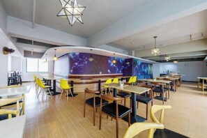 Ein Restaurant mit einer gebogenen Theke, mehreren Tischen und Stühlen.