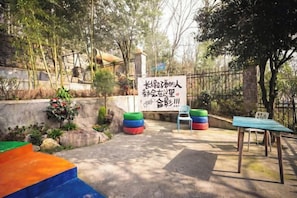 A courtyard with a sign, a table, and colorful seating. - Saixi Hotel (Chongqing)