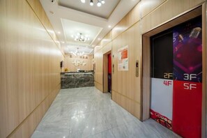 A hotel corridor with a reception desk, elevator doors labeled 2F to 5F, and a chandelier on the ceiling. - ShangHai Xinshang Boutique Hotel（MinHang PuJiang Brunch） (Shanghai)