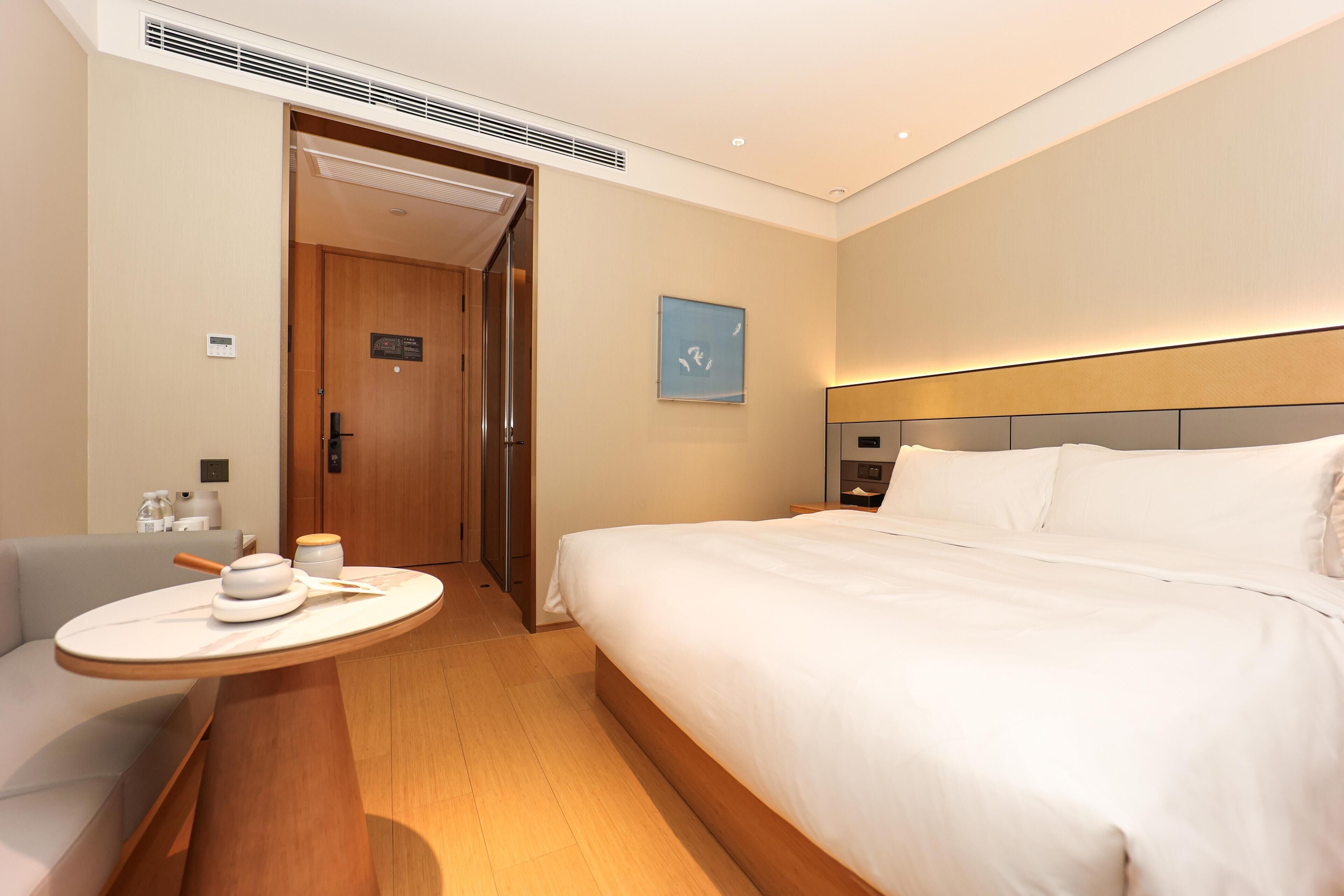 Quarto de hotel com cama, mesa de cabeceira e um pequeno espaço de estar com uma mesa.