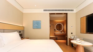 Une chambre d’hôtel avec un lit, un miroir rond, une petite table et un téléviseur.