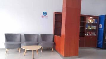 A reception area with a seating arrangement, a pillar, and a bookshelf.