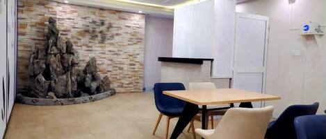 A conference room with a wooden table, blue and white chairs, a stone wall feature, and recessed ceiling lighting.