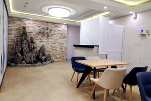 A conference room with a wooden table, blue and white chairs, a stone wall feature, and recessed ceiling lighting. - Hanting Hotel (Shanghai Lujiazui Zhangyang Road) (Shanghai)