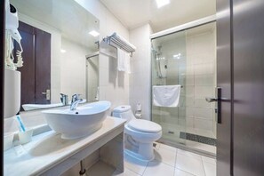 Een moderne badkamer met een groot wit wastafelmeubel, toilet en een douche met glazen wanden.