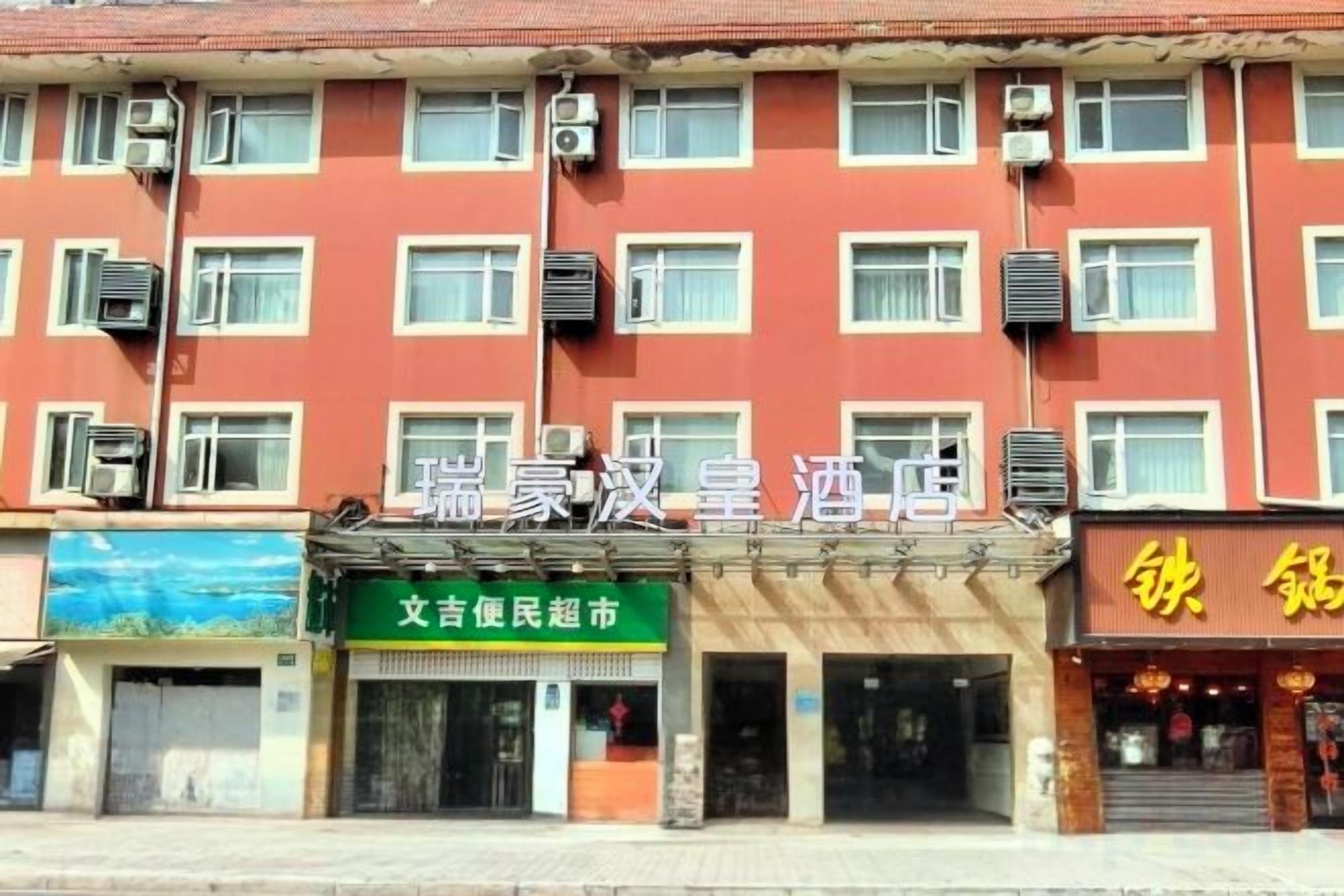 A multi-story building with a red facade and multiple air conditioning units.