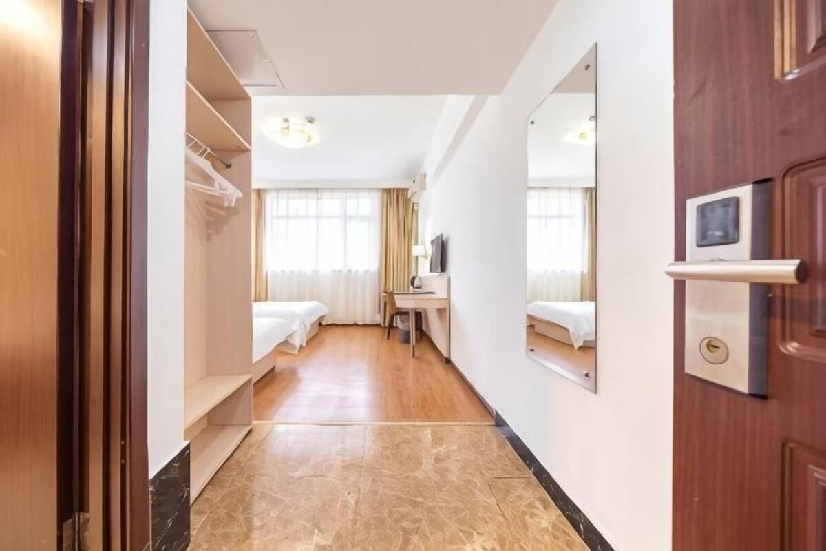 Une chambre d’hôtel avec un lit, un bureau, un miroir et une armoire.