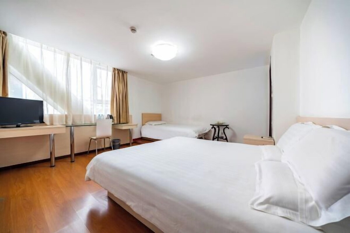 Een hotelkamer met een bed, een bureau, een stoel, een televisie en een kleine tafel.