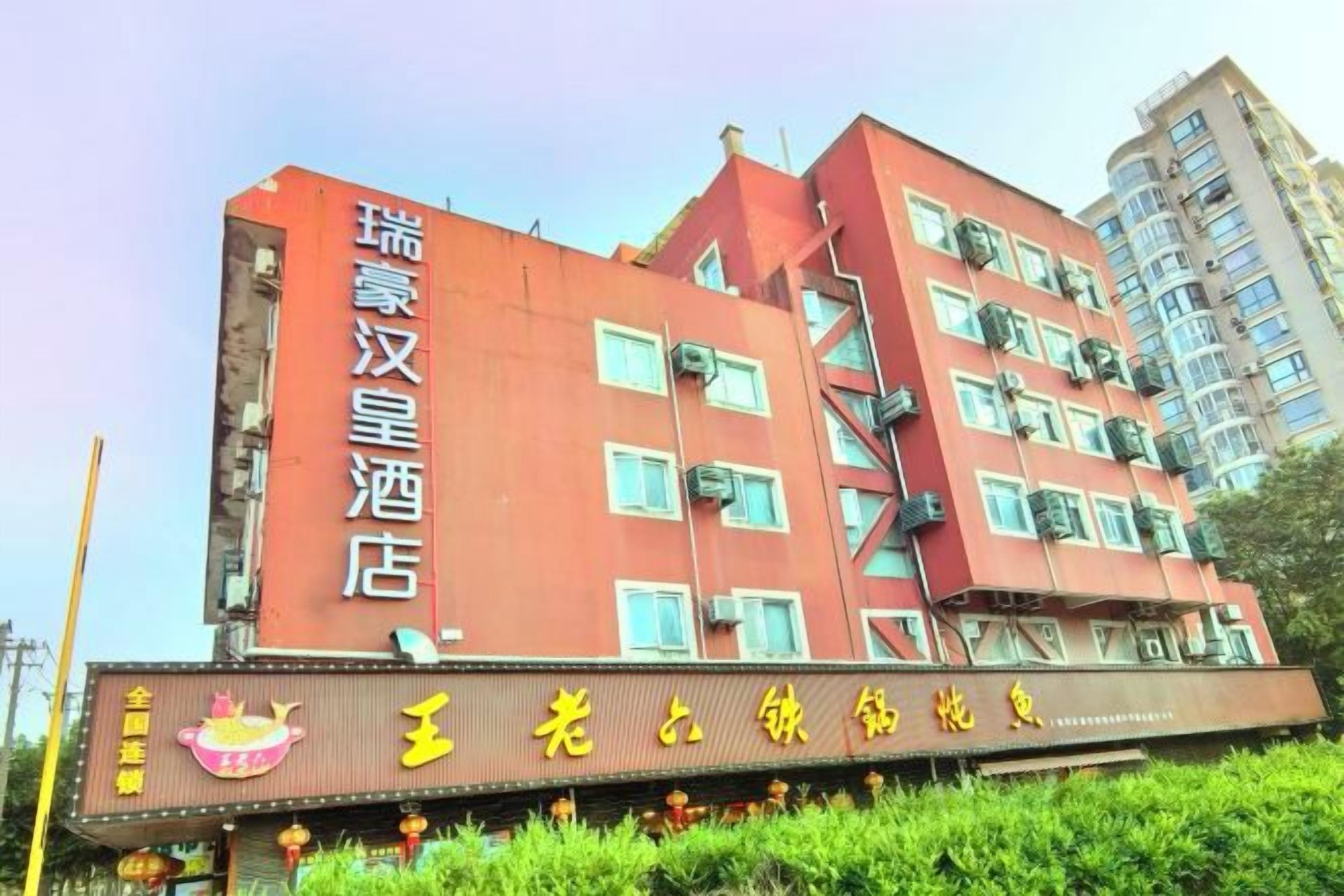 A multi-story hotel building with a prominent signboard and a balcony.
