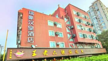 A multi-story hotel building with a prominent signboard and a balcony.