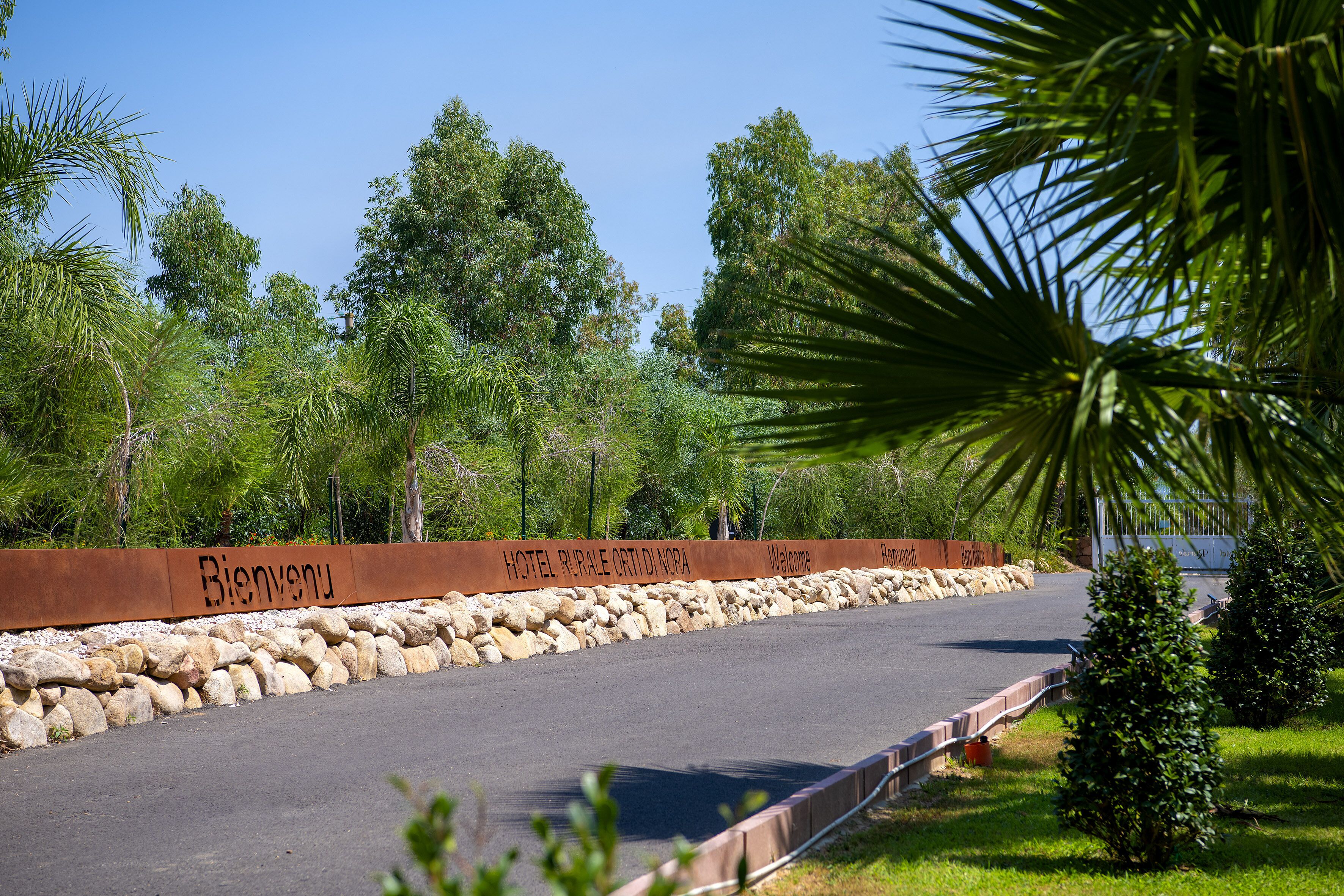 A road leading to a hotel with a 'Welcome' sign and a 'Hotel Rurale' sign.