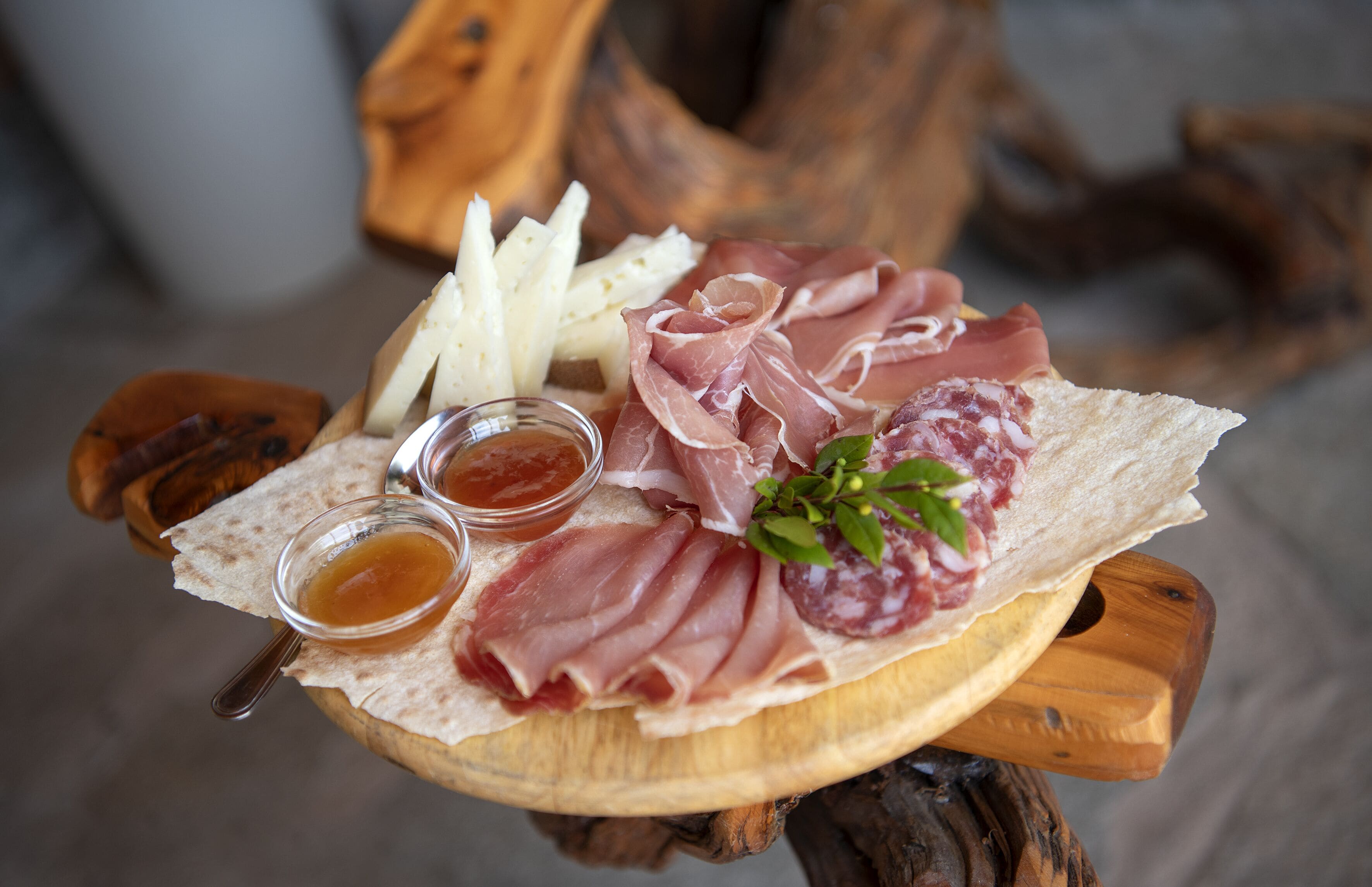 Una tabla de madera con diversas carnes, quesos y condimentos.