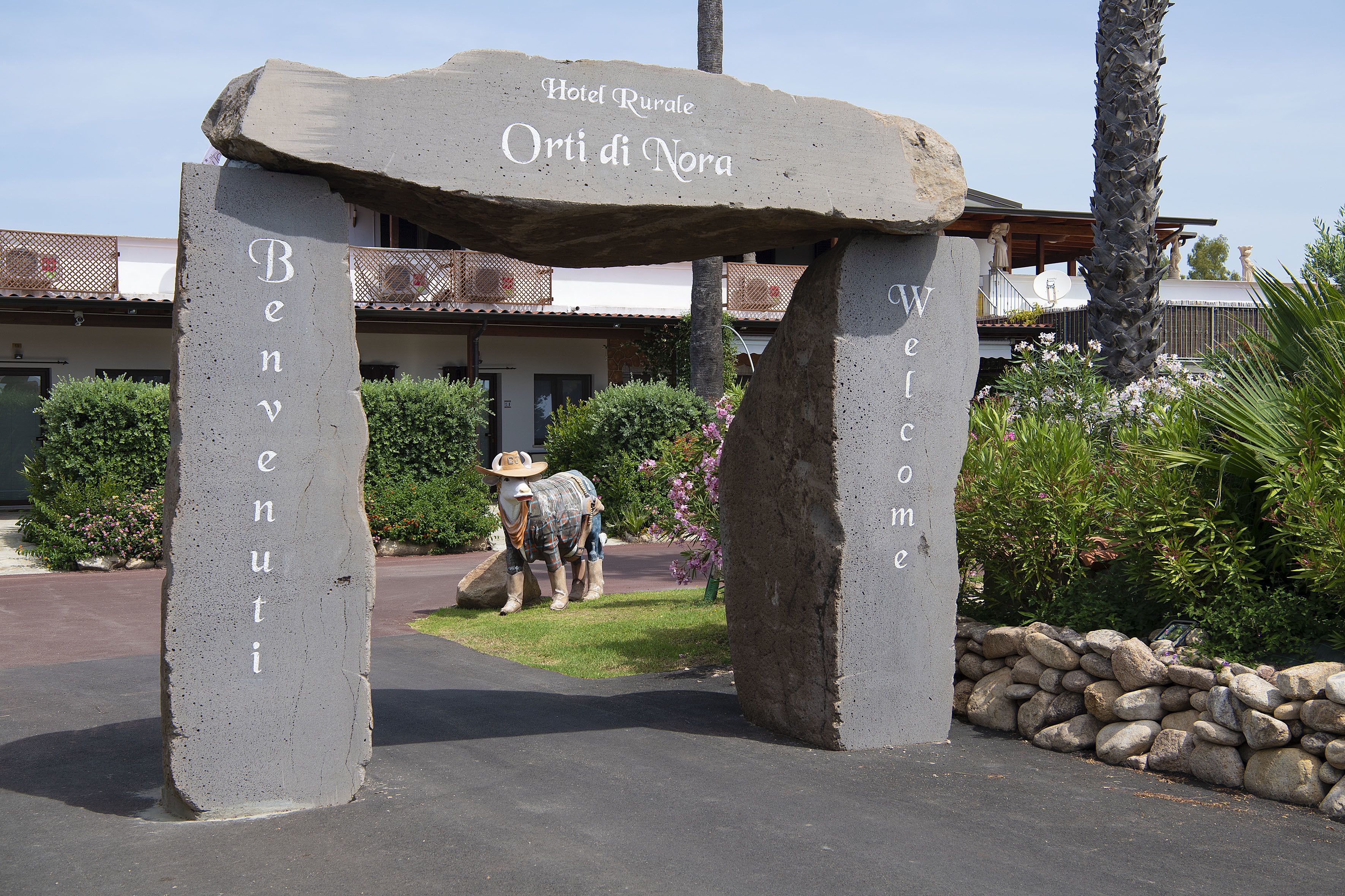 A stone archway with the inscription "Hotel Rurale Orti di Nora" welcoming guests.