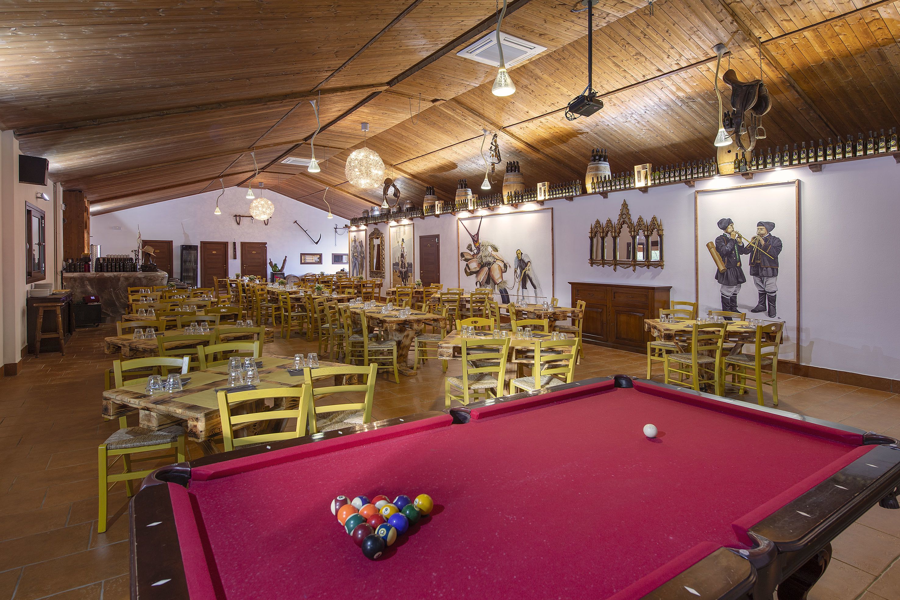 A billiards hall with multiple tables and chairs, wooden ceiling, and wall-mounted decorations.