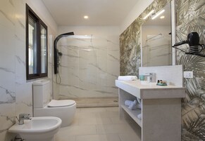 A modern bathroom with a bidet, toilet, and shower.