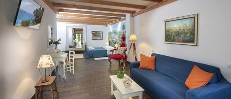 A living room with a blue sofa, wooden beams, a white coffee table, and a red chair.