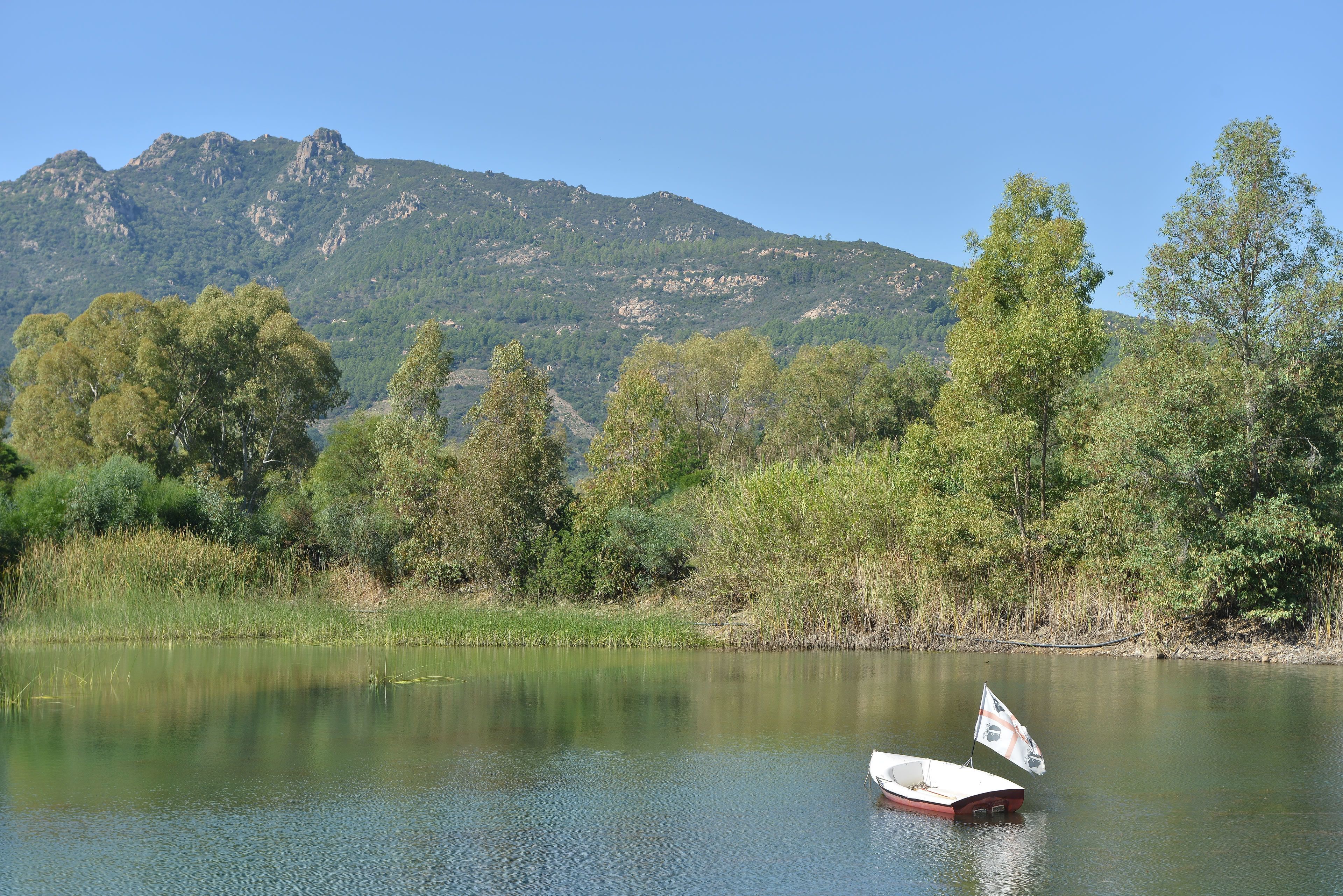 A calm lake with a small boat and a mountain in the background.