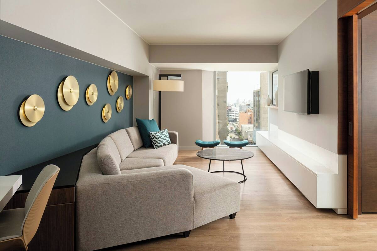 A modern living room with a sofa, a coffee table, and a TV mounted on the wall.
