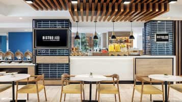 Un bistró moderno con techo de madera, una isla central con equipo de cocina y zonas de estar con mesas y sillas redondas.