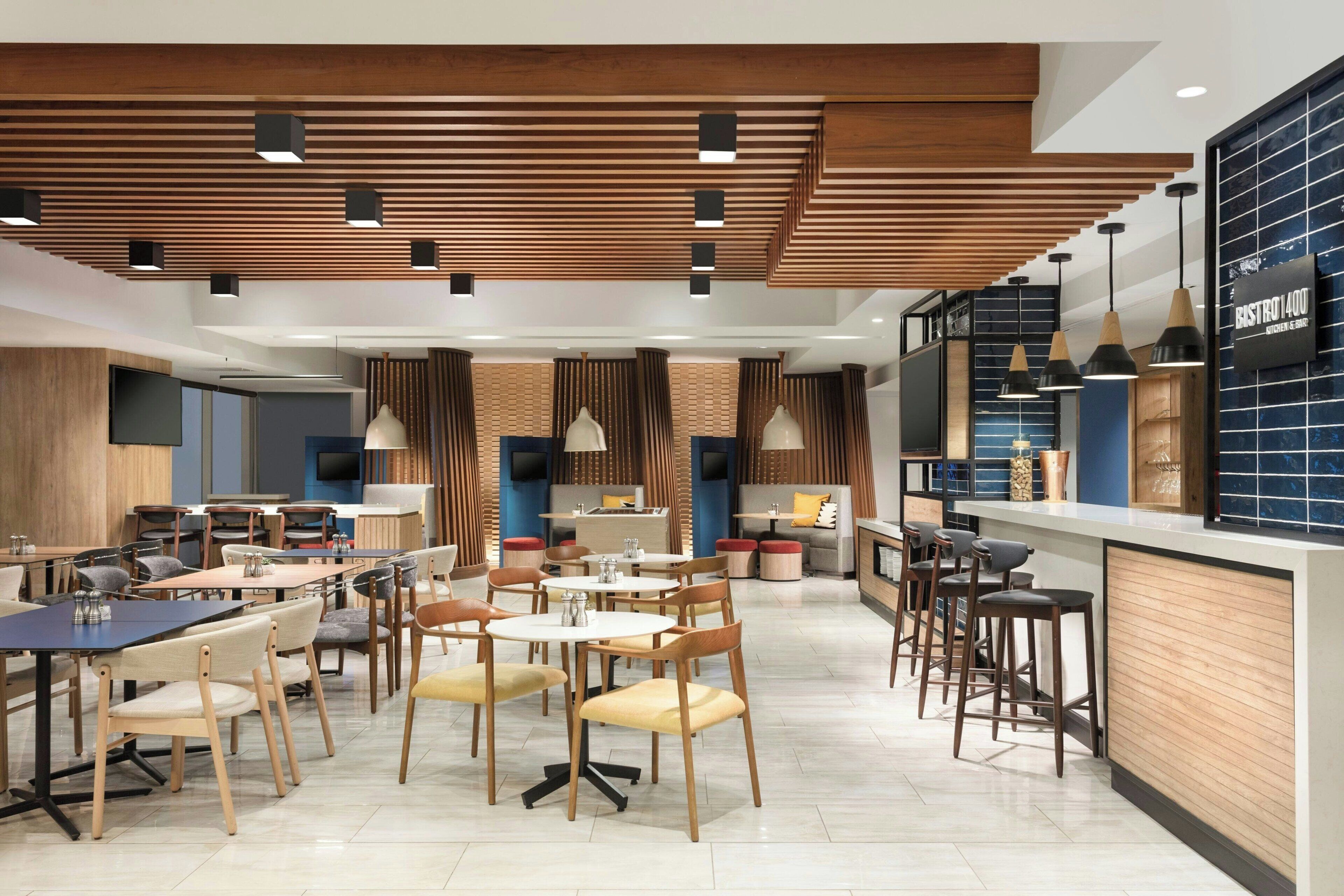 Un restaurante moderno con paneles de techo de madera, varias zonas de estar y una barra.
