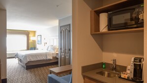 Ein Hotelzimmer mit Bett, Schreibtisch, Mikrowelle, Kaffeemaschine und Spüle.